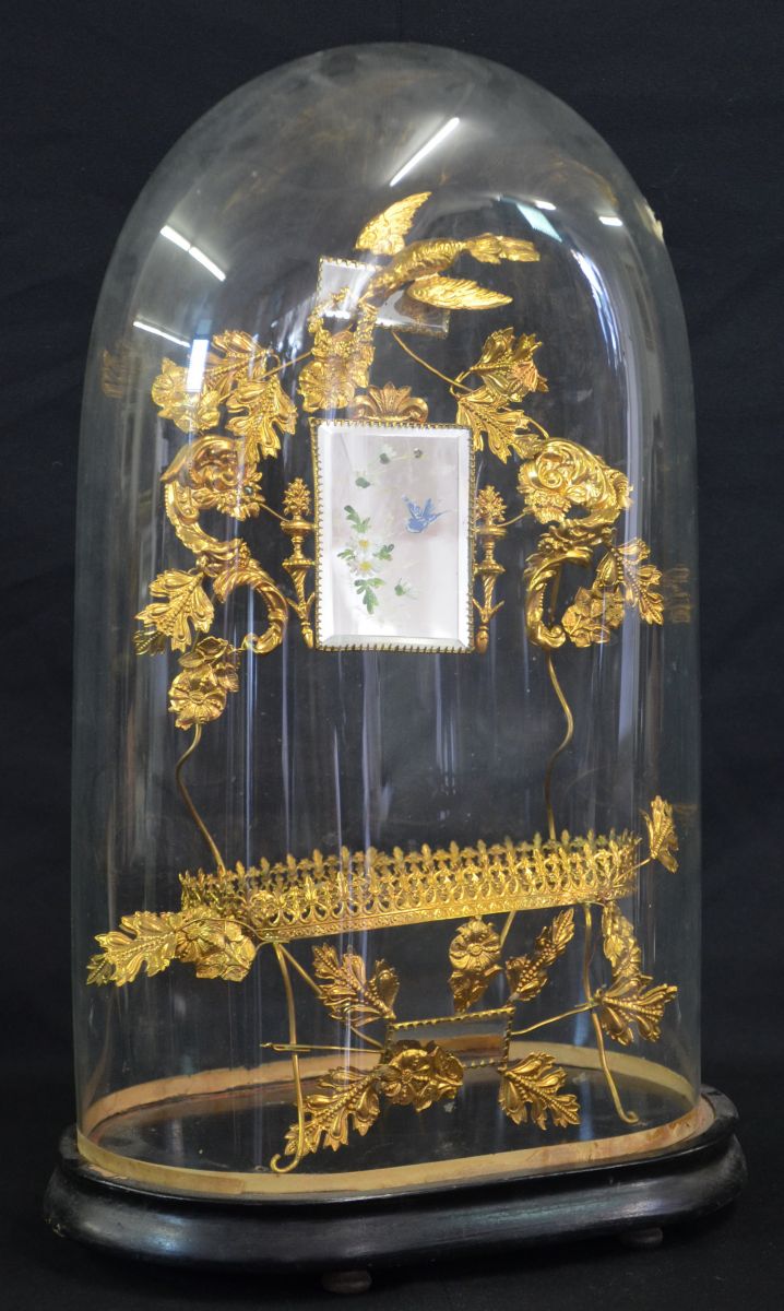  Gilded filigree, wreath and flower ornaments of metal underneath a glass globe on wooden stand. With...